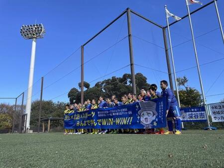 写真：事業の様子　垂れ幕を持って記念撮影するサッカー選手ら