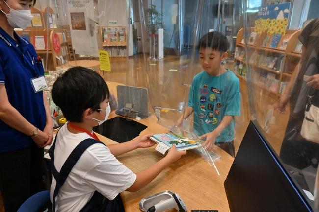 写真:貸し出す本を手渡す子ども1日図書館員