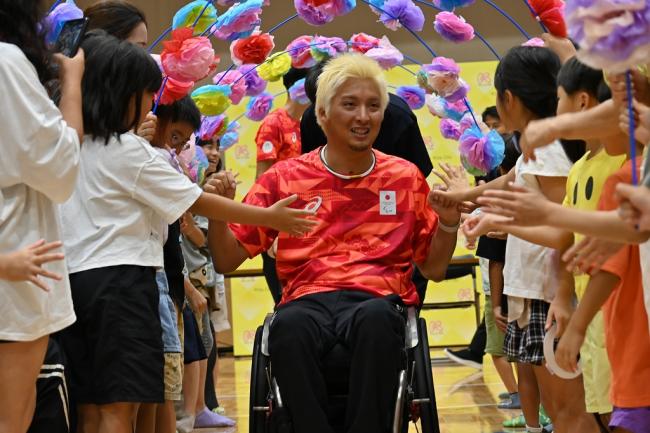 写真:子供たちに囲まれながら移動する小川選手