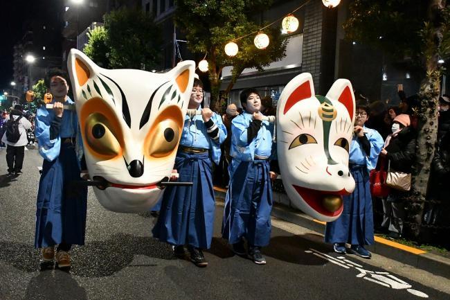 写真:巨大な狐の面を持って行進する人たち
