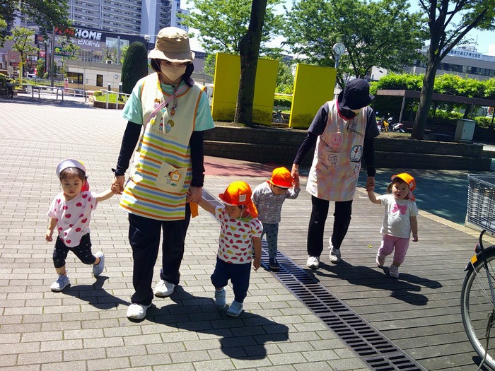 お散歩では、安全のため保育士と手をつないで歩いています。