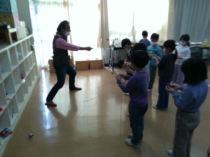 地域の方にコマの投げ方を教えていただいている様子