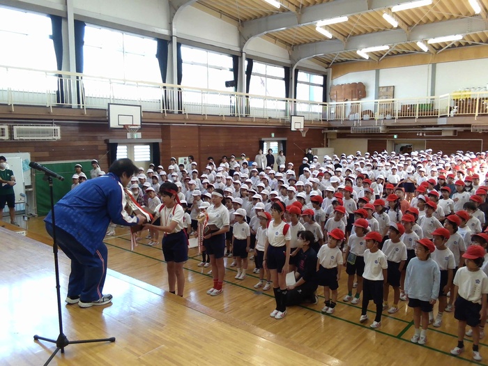 校長が児童にトロフィーを渡している様子