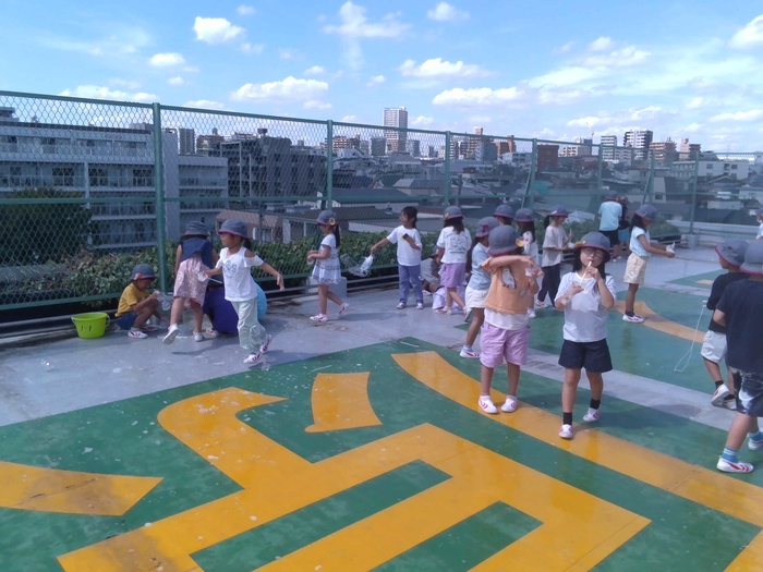 児童が屋上でシャボン玉遊びをしている様子