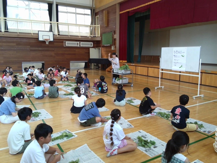 栄養士が枝豆の枝切りについて説明している様子