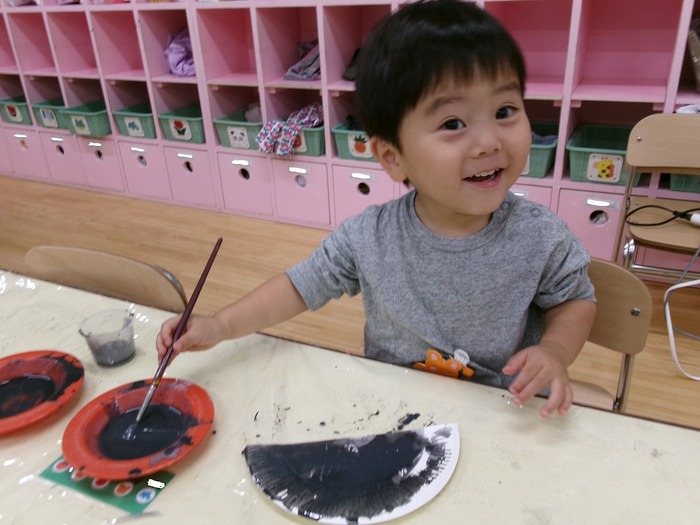 紙皿に黒の絵の具を塗っているところ