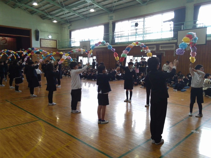 花のアーチを持って6年生を見送る4年生