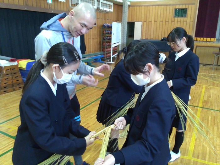 二人一組でわらをねじっているところ