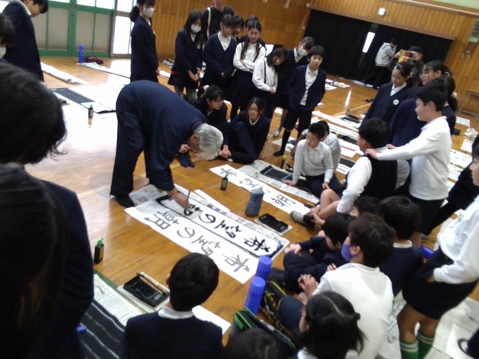 雨宮先生が児童の習字道具を使って書き初めをするところ