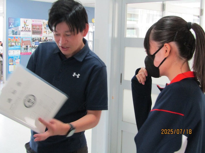 担任から通知表を渡されている様子